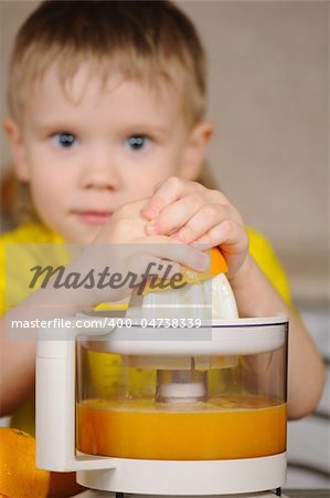 The child in a yellow vest to wring out juice  from an orange