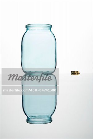 Coins and empty glass jar on white background