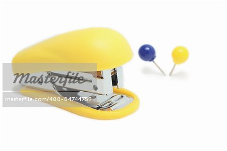 Yellow stapler and two pushpins isolated on white background