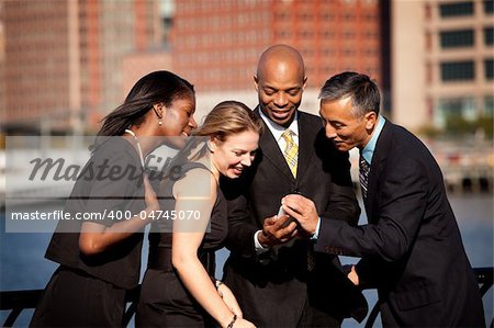 A group of business people crowded around a cell phone