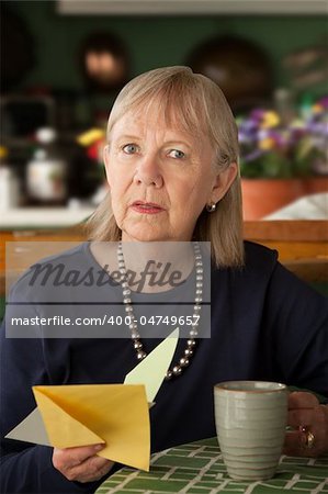 Senior woman at home reading sympathy card