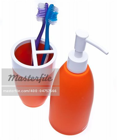 Soap bottle and toothbrush holder with toothbrushes isolated on white.