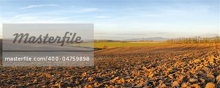 Panorama of landscape with blue sky above the plowed fields