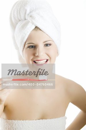 Young beautiful woman with healthy strong teeth and white towel on her head holding tooth brush in bathroom