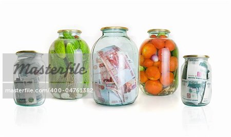 Glass jars with cucumbers tomatoes and money on a white background