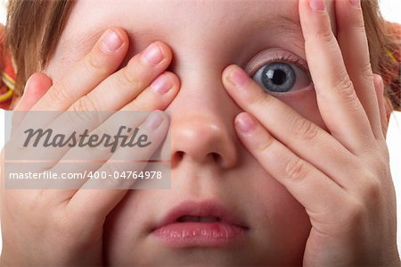 Little girl peeping through hand with one eye macro shot