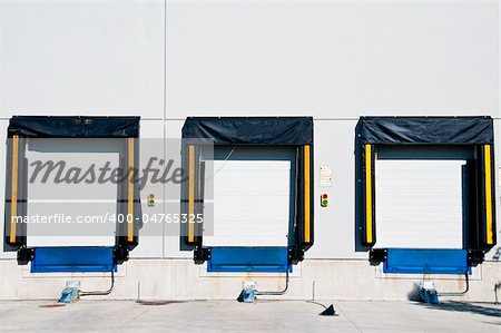 Three freight  loading doors with a set of green and red light to aid driver.