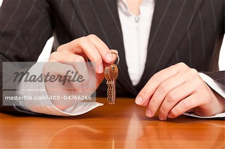 Business woman holds house key for handing over of keys. Isolated on white background.