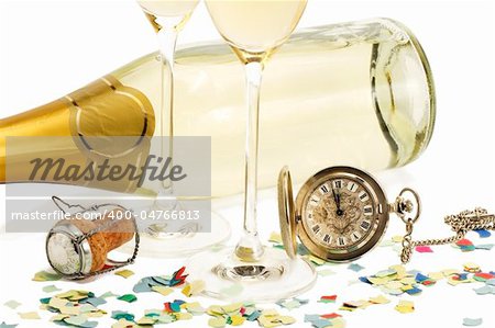 two glasses with champagne, old pocket watch, cork and confetti in front of a champagne bottle on white background