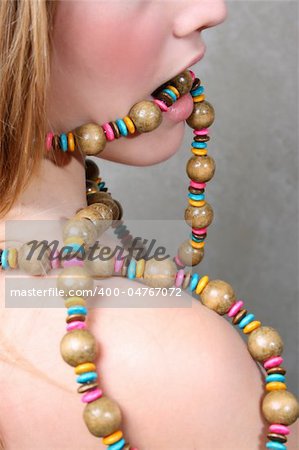 Beautiful female model a string beads in her mouth