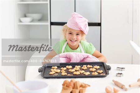 Happy little girl holding a plate with her cookies ready to eat standing in the kitchen