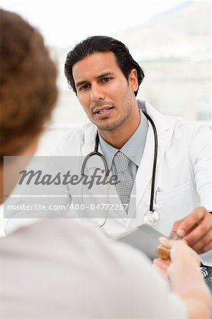 Serious doctor giving pills to his patient during an appointment in his office