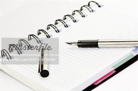 Paper notebook with fountain pen on white background