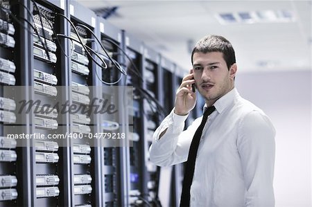 young business man computer science engeneer talking by cellphone at network datacenter server room asking  for help and fast solutions and services