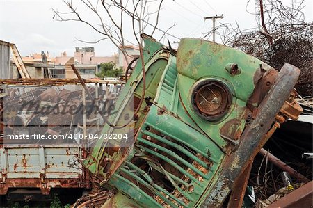Rusty vintage car and scrap metal at a junkyard.