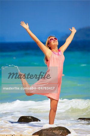 Young woman with hands up at the tropical beach