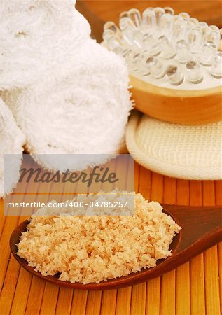 bath salt on a wooden spoon with bath accessories close up
