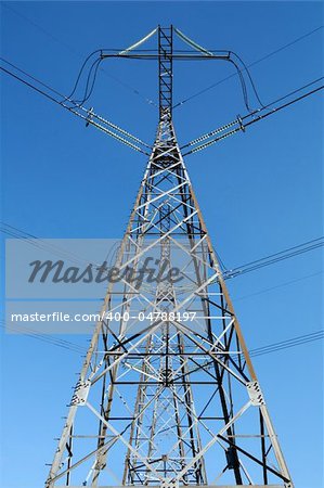 Power lines and electric pylon against a blue clear sky.
