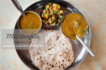 Traditional Indian cuisine vegetarian thali served in small bowls on a round tray.