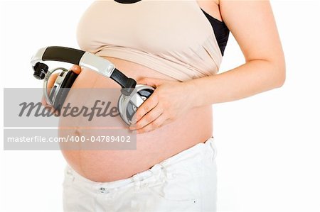 Pregnant woman with headphones on her belly isolated on white.  Close-up.