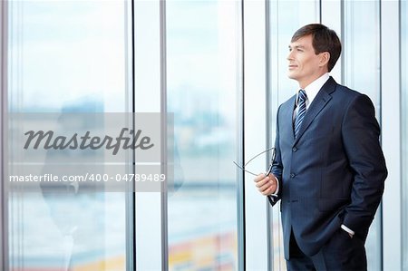 A man in a business suit looks out the window