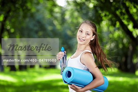 Jeune fille avec une bouteille d'eau et de tapis de gymnastique tourner