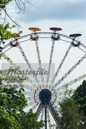 Popular attraction in park - a Ferris wheel on a background of the cloudy blue sky