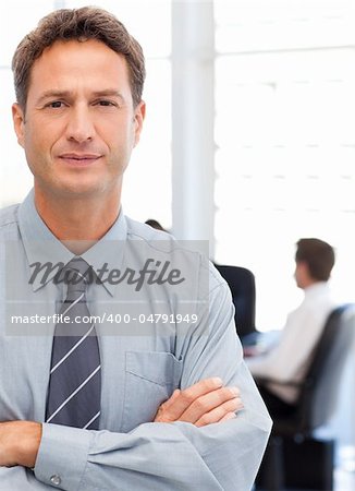 Assertive businessman standing in front of his team while working at a table in the background