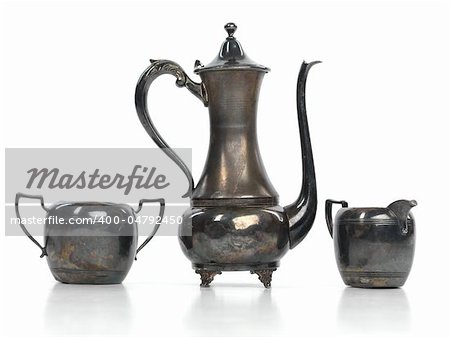 Antique metal tea pot, a milk jug and a sugar bowl isolated on white background