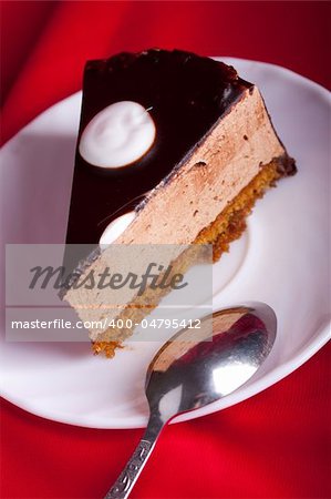 chocolate cake with spoon on the plate on red silk background. Shallow focus