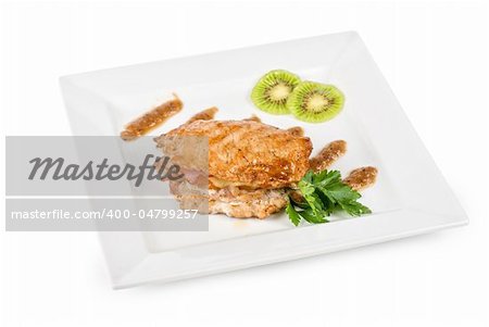 Cooked pork chop with kiwi and parsley on a white