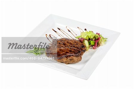 Beef steak on a white plate with vegetables on a white