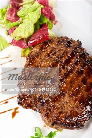 Beef steak on a white plate closeup with vegetables