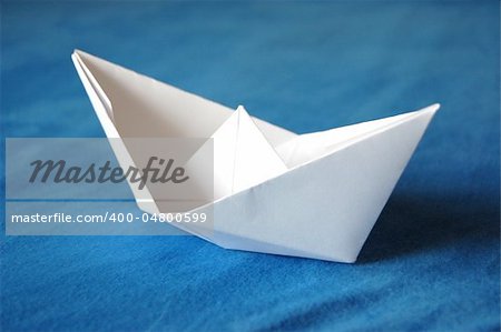 origami paper boat isolated on blue water