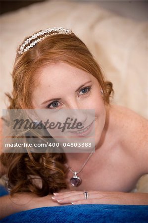 red head sexy beautiful bride laying down on her elbows with cleavage visible and leaning on her hands whilst smiling