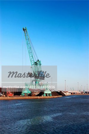 Port crane with blue sky in background and water in foreground