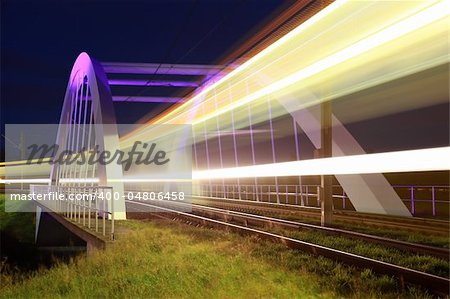 A light rail is passing an illuminated bridge near Stuttgart Germany