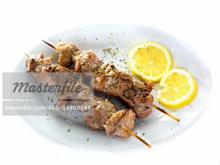 A plate with original greek Souvlaki (also known as Kalamaki) and lemons, isolated on white background