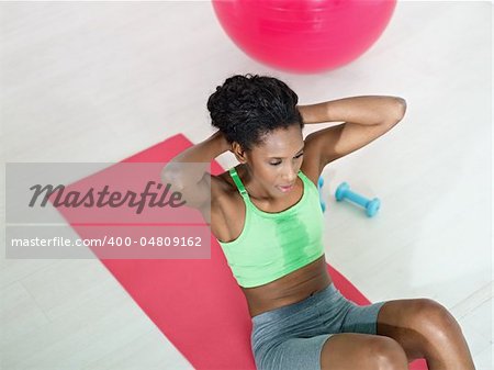 young african american woman in green sportswear exercising abdominals on pad in gym. Horizontal shape, high angle view, copy space