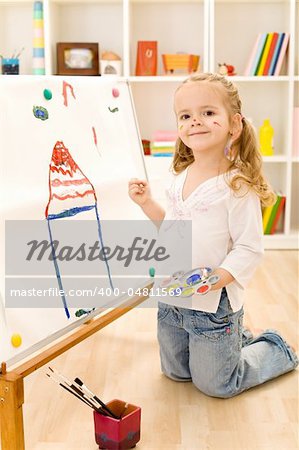 Little smiling artist girl painting her dream house on a large paper canvas