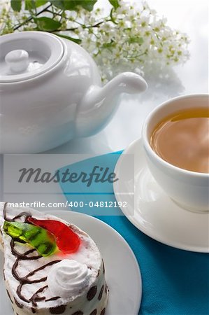 Cup of bird-cherry tea and biscuit cake with pieces of colored jelly