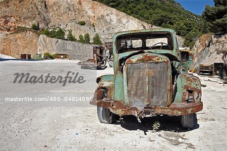Rusty vintage car and industrial machinery at a quarry.