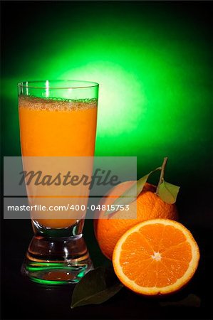 Natural orange juice in a glass and orange fruit, on black background shooting with green gel