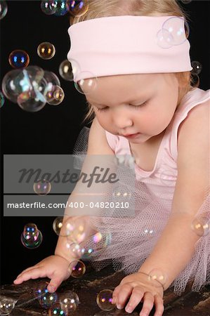 Baby ballerina playing amongst lots of bubbles