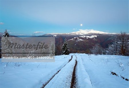 Winter night mountain dirty road, forest with last autumn foliage and Moon on twilight sky (Petros and Goverla Mountain, Carpathian, Ukraine)