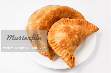 Cheese empanada, meat empanada or chicken empanada on a white plate.   Empanada (meat pie) - traditional snack originally from Spain.