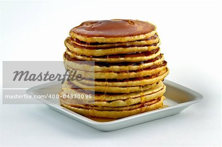 Pancakes with syrup poured over at dish on white background