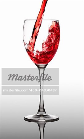 red wine pouring into glass on gray background