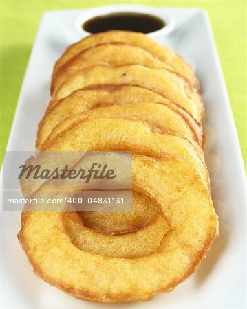 Popular Peruvian dessert called "picarones" made from squash and sweet potato and served with "chancaca" syrup (kind of honey), which is the black sauce in the back (Selective Focus, Focus on the upper part of the first ring)