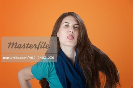 Cute Caucasian girl dressed in blue sticks her tongue out